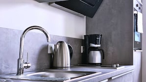 Eine moderne Küche mit Spüle aus Edelstahl, einem Wasserkocher und einer Kaffeemaschine.