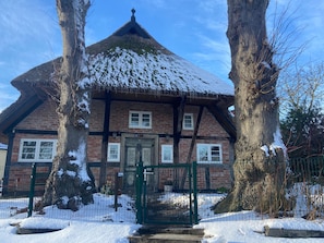 A traditional building with a thatched roof, brick walls, and a green gate.