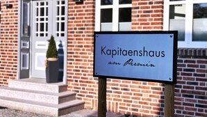Ein Schild vor einem Backsteinhaus mit Tür und Fenstern.