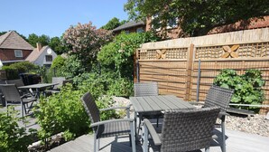 Eine Terrasse mit Gartenmöbeln, einem Holzzaun und viel Grün.