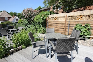 A deck with outdoor furniture, a wooden fence, and greenery.