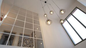Um interior moderno com luminária de teto geométrica e janelas amplas.