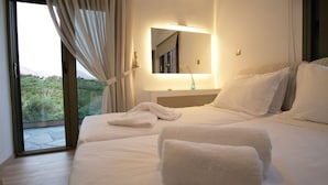Quarto de hotel com uma cama grande, mesa de cabeceira com espelho e vista para o verde lá fora.