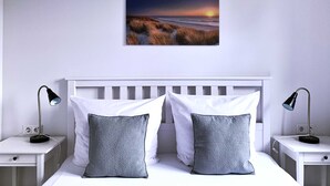 A bedroom with a white headboard, two bedside tables with lamps, a white bed with two pillows, and a framed picture on the wall. - FW Port Bridge, Germany (Wustrow)