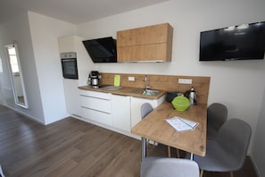 A modern kitchen with a microwave, oven, and a flat-screen TV mounted above the counter.