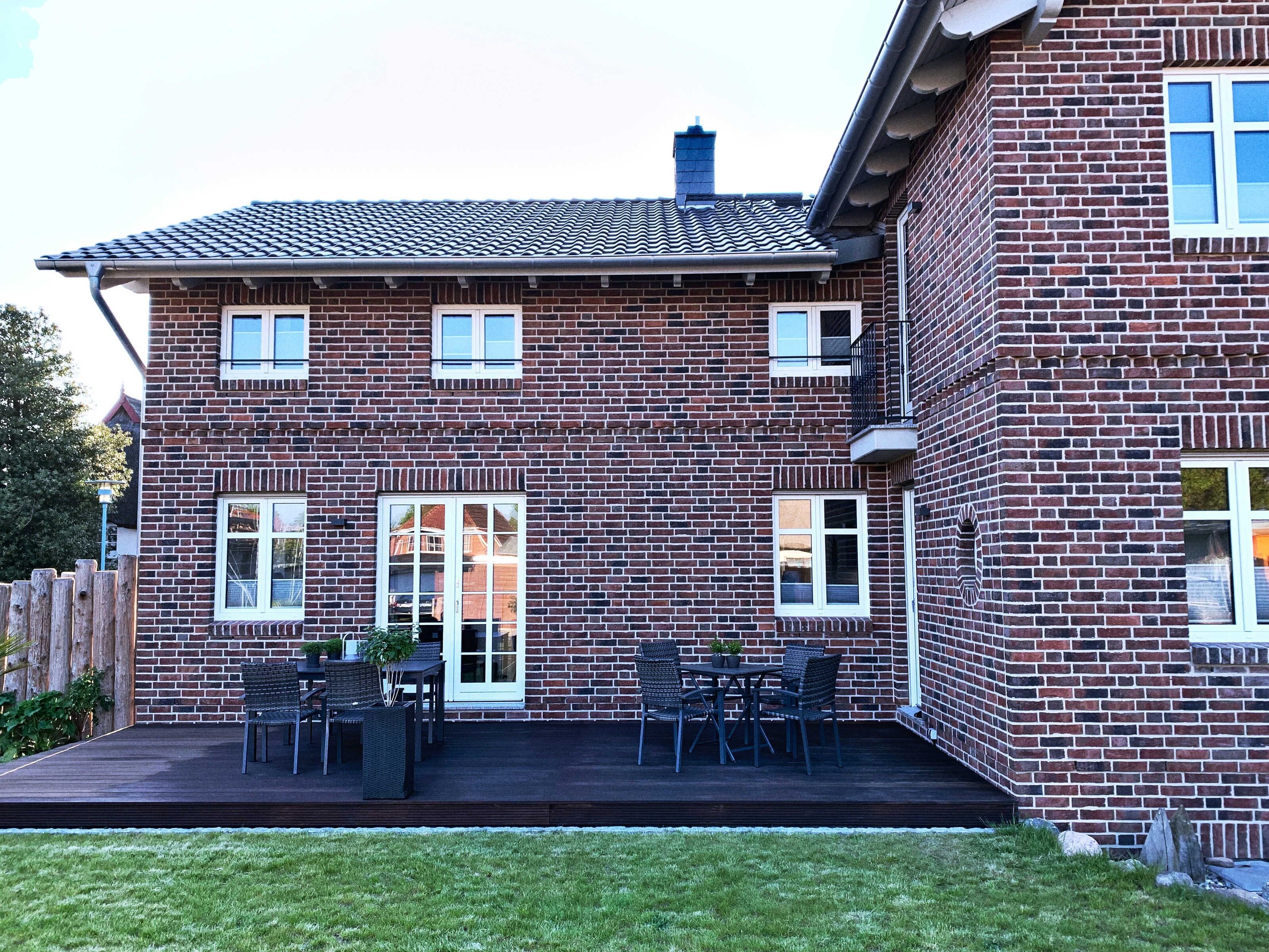 Et toetagers murstenshus med en patio og havemøbler.