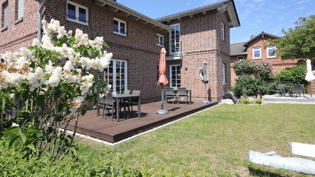 A brick building with a deck, outdoor furniture, and a garden area. - FW Port Bridge, Germany (Wustrow)