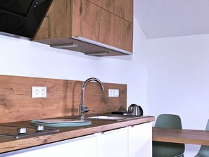 A kitchen with a wooden countertop, stainless steel sink, and a built-in range hood. - FW Backbord Peildeck (Wustrow)