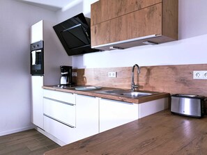 A modern kitchen with a built-in oven, a coffee maker, a sink, and a toaster. - FW Backbord Peildeck (Wustrow)