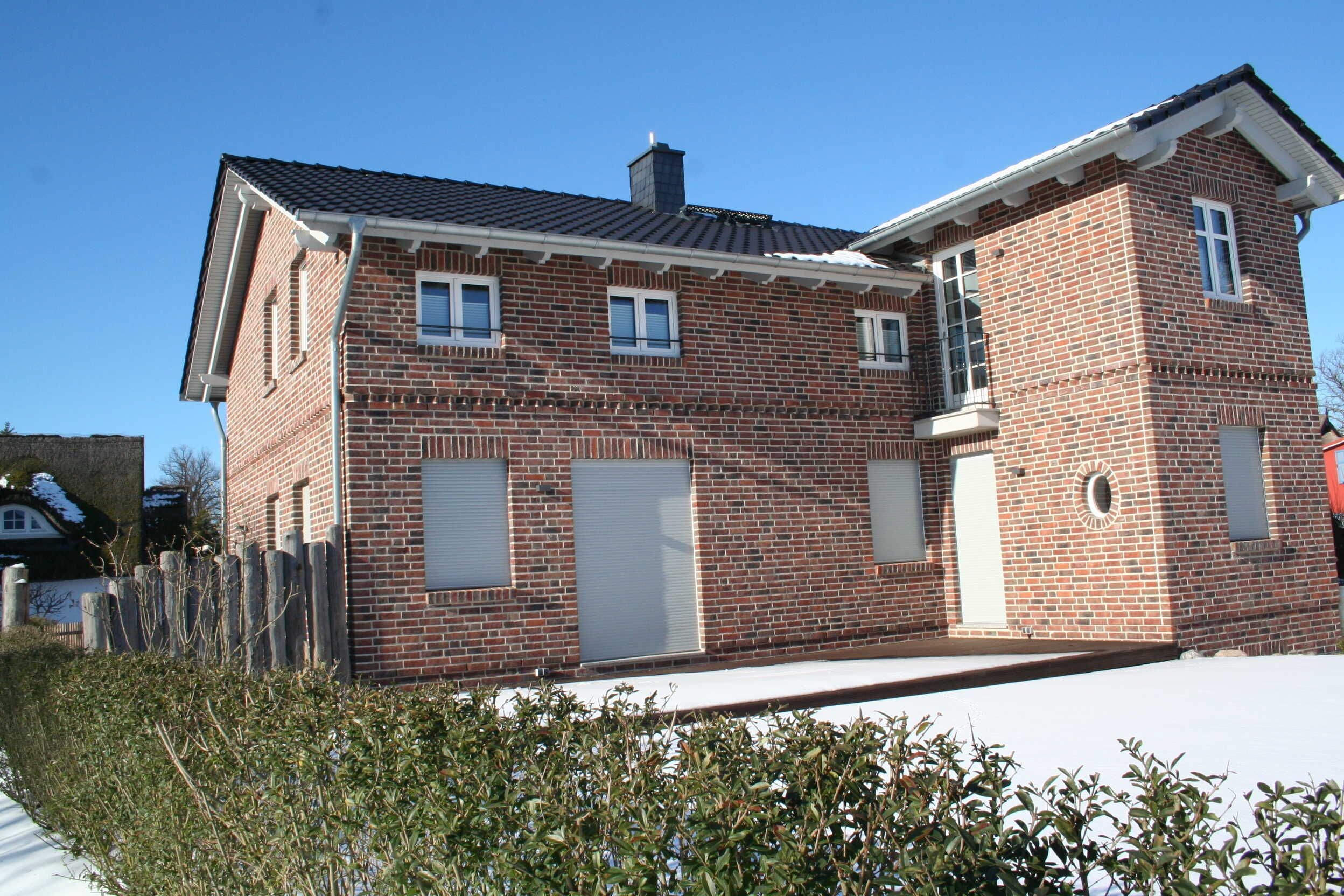 Een tweelaags bakstenen huis met schuin dak, een oprit en een klein voortuintje.