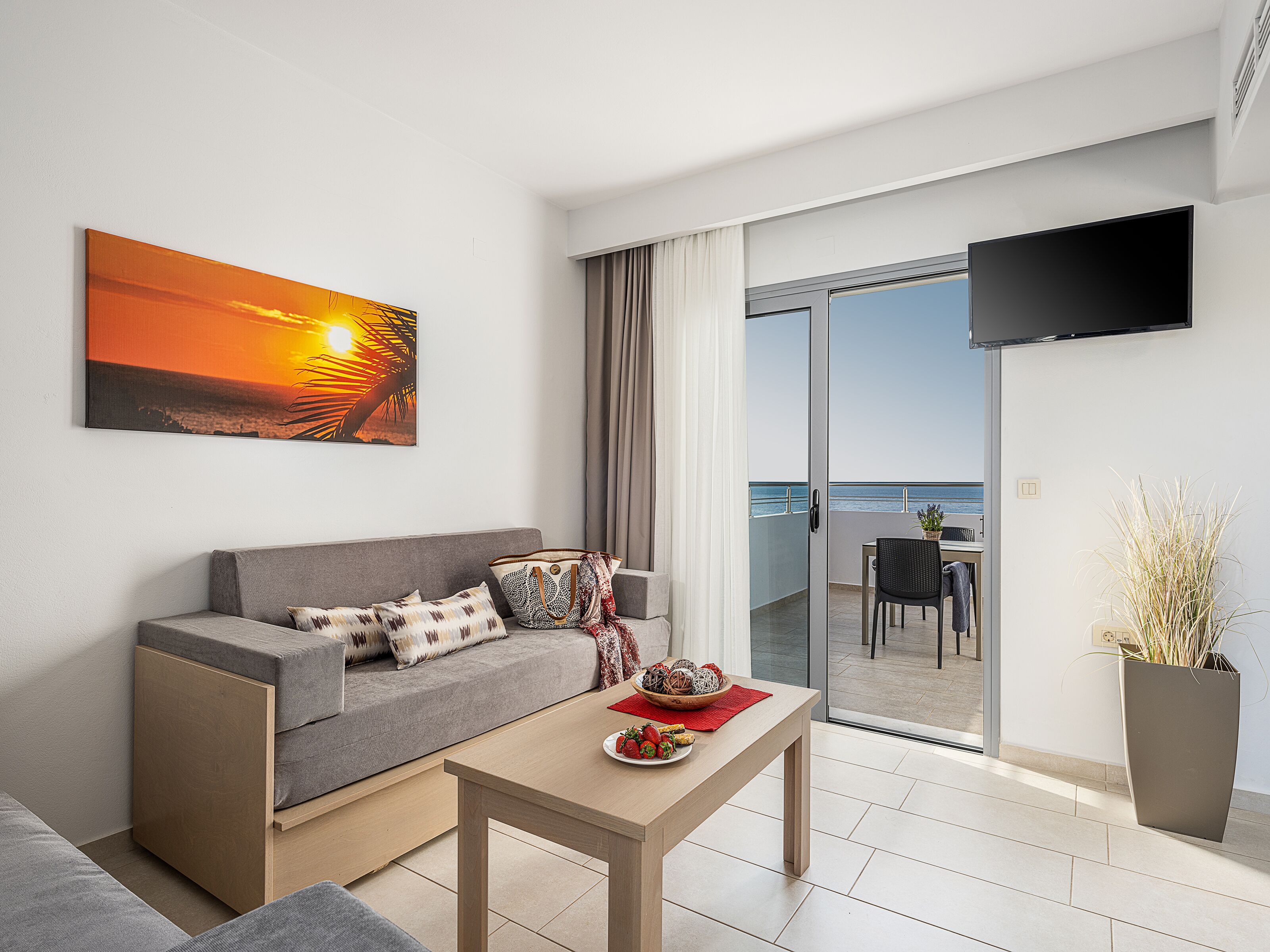 Una sala de estar moderna con un sofá, una mesa de centro y un televisor montado en la pared.