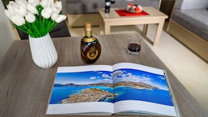 Un libro abierto sobre una mesa, una botella y un jarrón con tulipanes blancos.