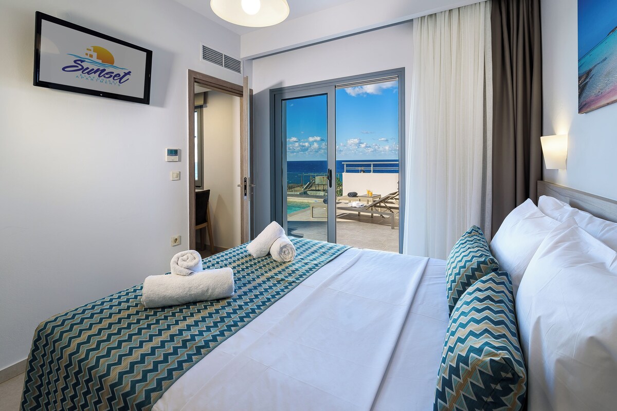 Een hotelkamer met een bed en uitzicht op de oceaan door een schuifdeur, met een bord aan de muur.