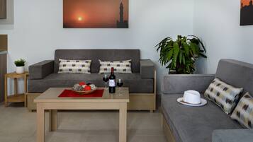 A modern living room with two grey sofas, a wooden coffee table, and a large potted plant.