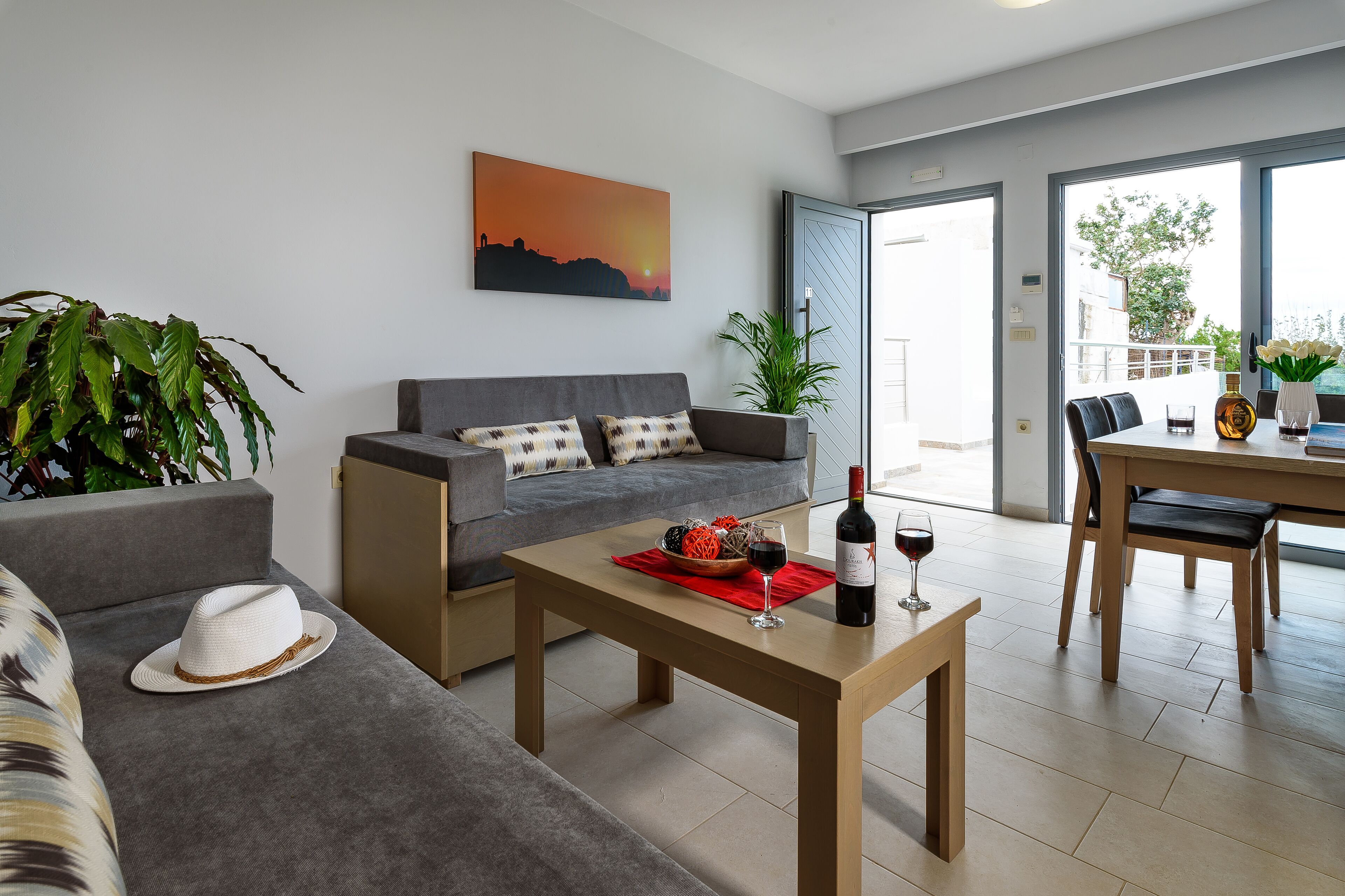 En moderne stue med sofa, spisebord med stole, sofabord og et maleri på væggen.