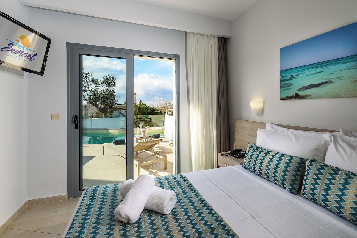 A hotel room with a bed, a painting of a beach, a sliding door to a balcony, and a sign on the wall.