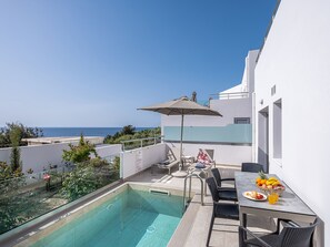 A poolside area with a view of the sea, a table with fruit and a drink, and outdoor seating. - Sunset Elafonisi Apartments (Kissamos)