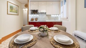 A dining area with a round table set for four, a kitchen in the background, and a framed picture on the wall. - Rialto Sant'Aponal Prestige by Wonderful Italy (Venice)