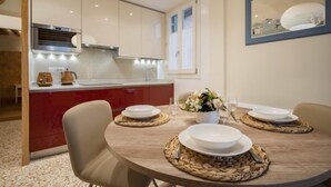 A modern kitchen with a central island, white cabinets, and a dining area with a round table set for four. - Rialto Sant'Aponal Prestige by Wonderful Italy (Venice)