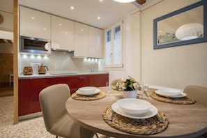 A modern kitchen with a central island, white cabinets, and a dining area with a round table set for four.