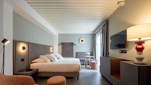 A modern hotel room with a bed, bedside table, lamp, seating area, and a TV. - Vis Urban Suites & Spa (Bari)