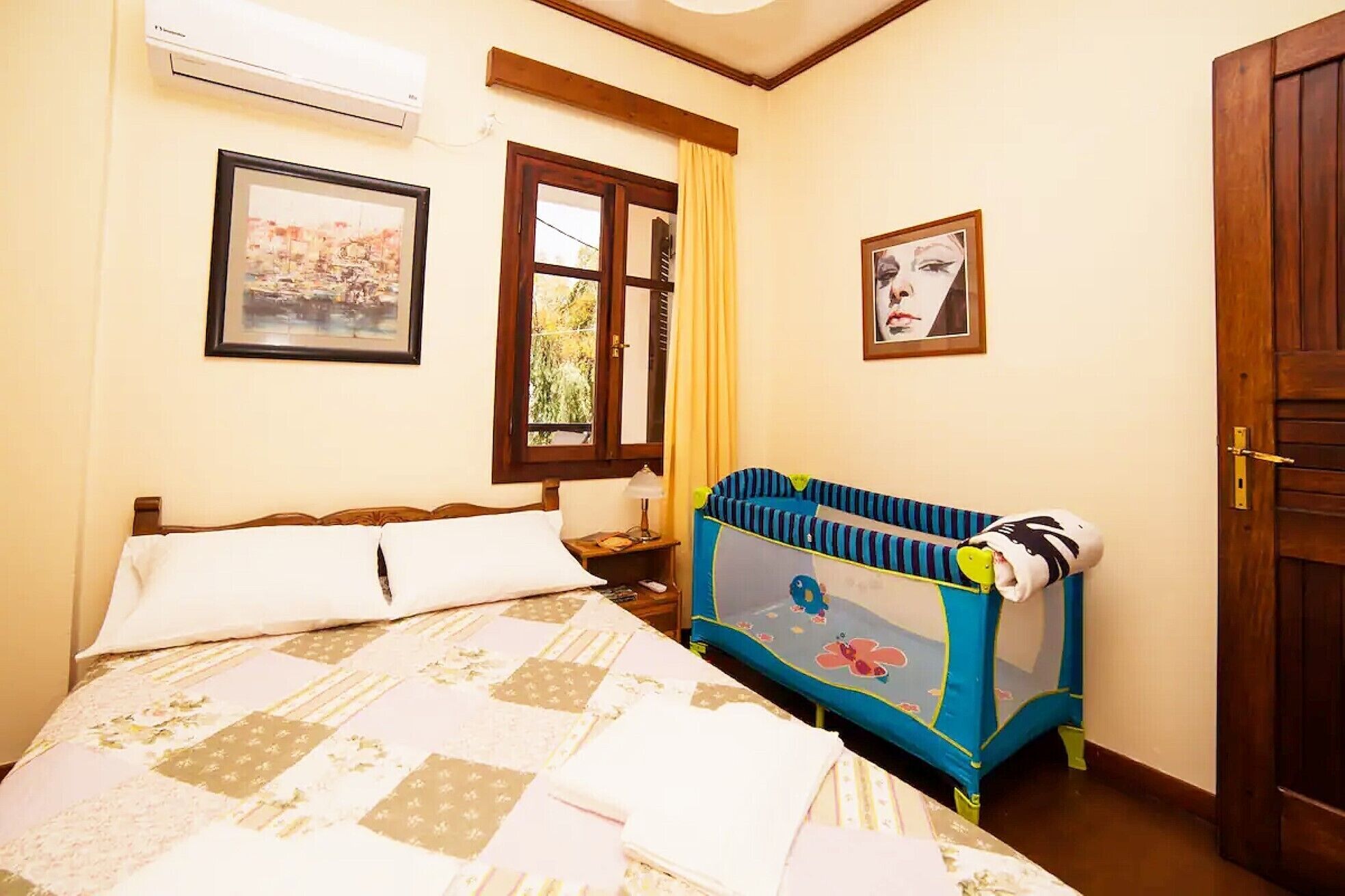 Un dormitorio con cama, ventana, cuna y puerta.