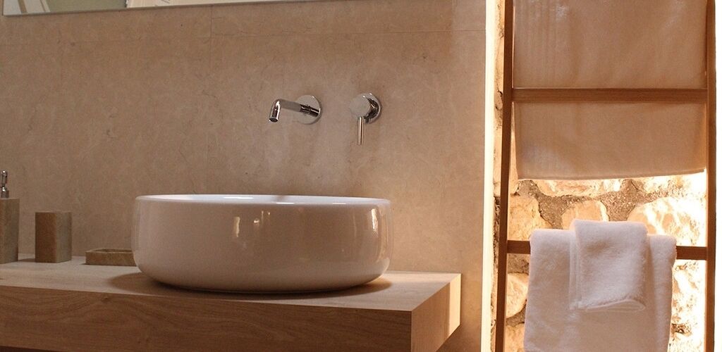 A bathroom with a large white sink, a wooden vanity, and a towel rack.