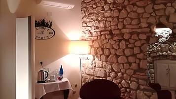 Ein Zimmer mit einer Steinsäule, einer Uhr, einem Tisch mit Wasserkocher und einer Tür.