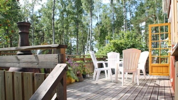 A wooden deck with white chairs and a table, surrounded by trees. - Holiday Home Gamla Vägen Konga (Tingsryd)