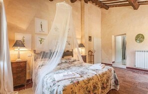A bedroom with a four-poster bed, a wooden floor, and a bed with a floral bedspread.