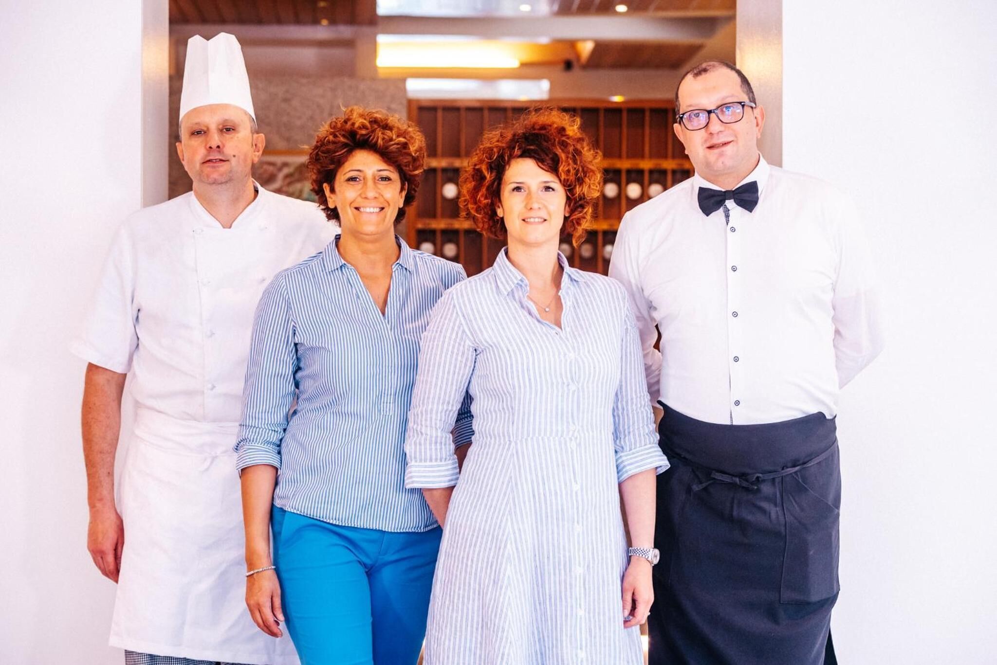 Un groupe de quatre personnes dans un cadre professionnel, probablement un restaurant ou un hôtel, avec un aménagement intérieur moderne.