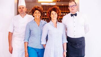 Un groupe de quatre personnes dans un cadre professionnel, probablement un restaurant ou un hôtel, avec un aménagement intérieur moderne.