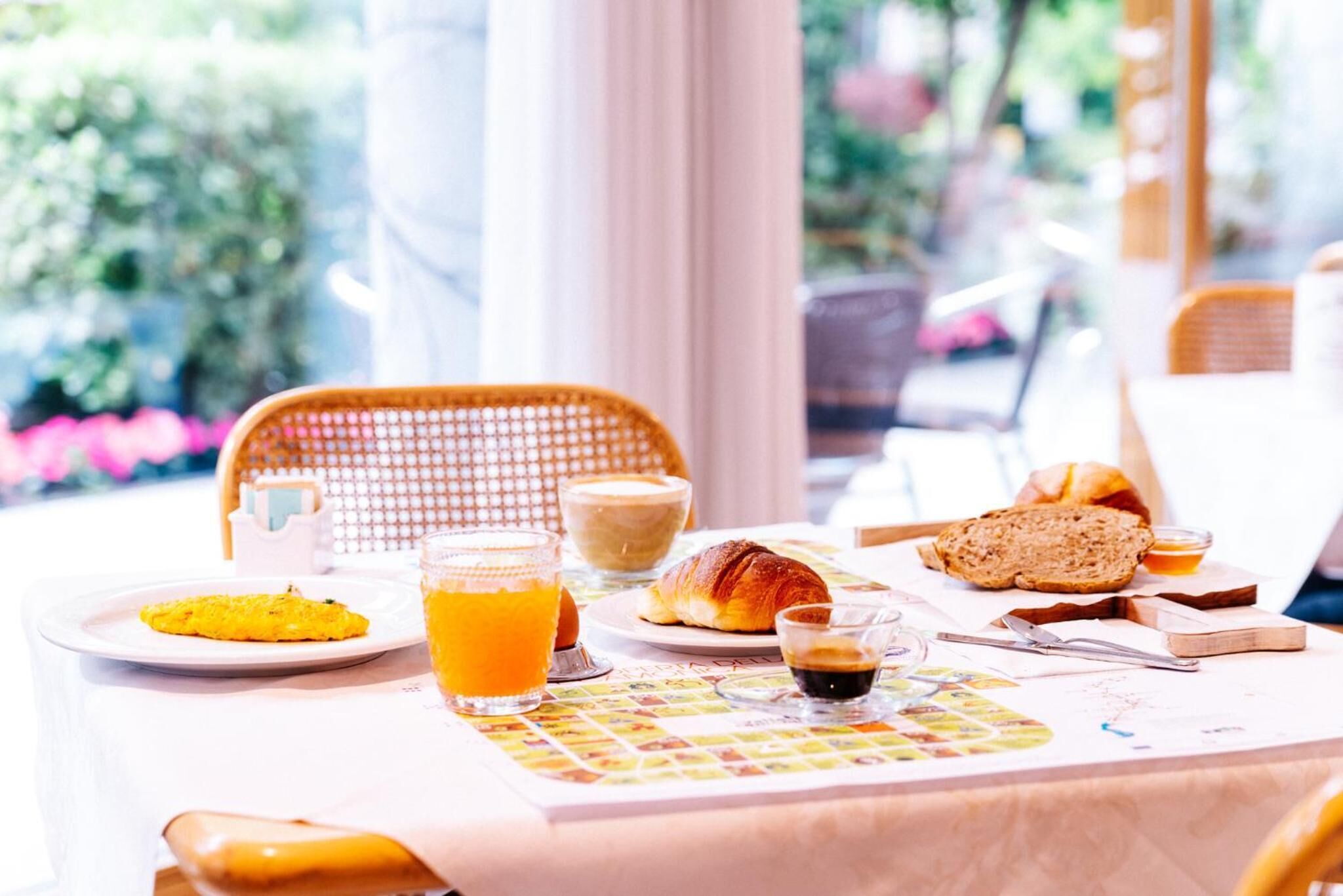 A breakfast table with croissants, orange juice, and coffee.