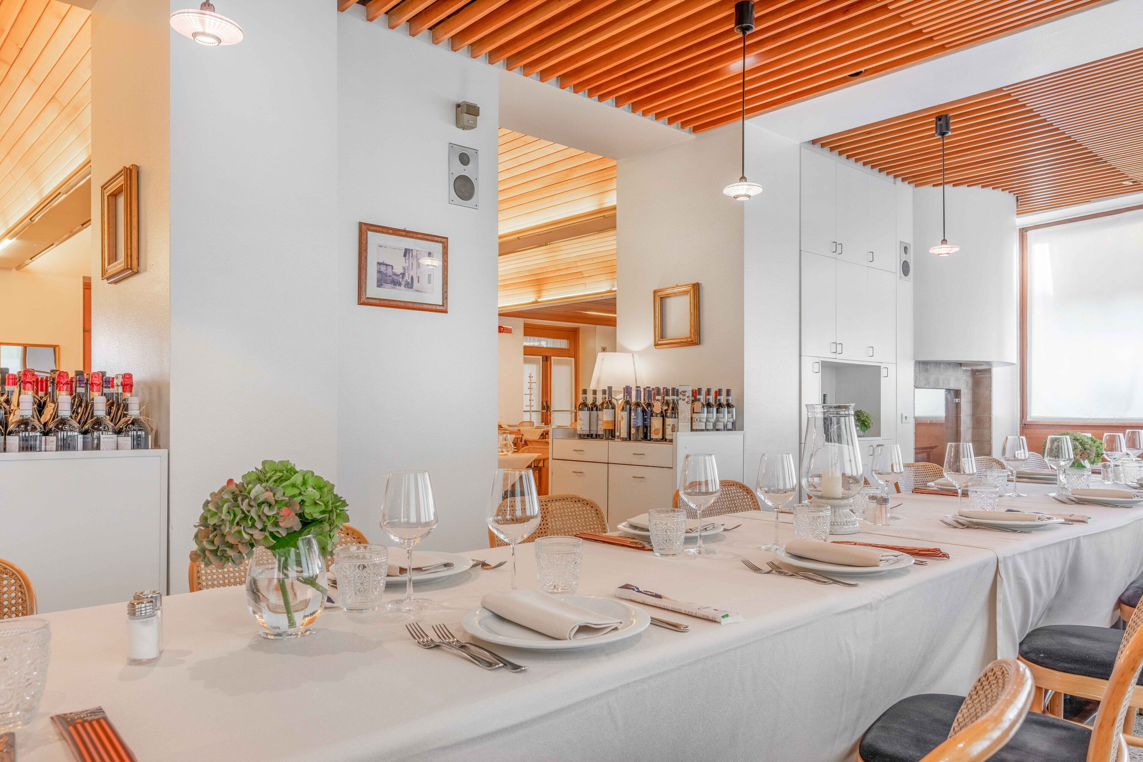 A long dining table set for a meal with white tablecloths, glassware, and neatly arranged cutlery.