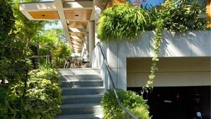 A modern building with a staircase leading to a covered area with plants. - Albergo Sorriso (Darfo Boario Terme)
