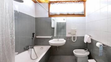 A compact bathroom with a bathtub, sink, and toilet.