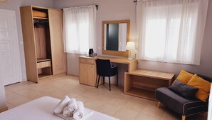 A hotel room with a bed, a desk, a chair, a wardrobe, and a sofa. - Chloe Apartments (Kefalonia)