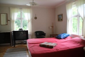 A bedroom with two beds, a desk with a television, a chair, and a window with curtains. - Holiday home Törnamåla Kilen (Tingsryd)