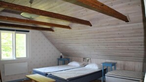 A bedroom with a sloped ceiling, a bed, a small table, and a window. - Holiday home Törnamåla Kilen (Tingsryd)