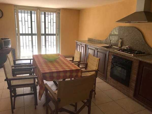 A kitchen with a dining table, chairs, a stove, and a window with bars.