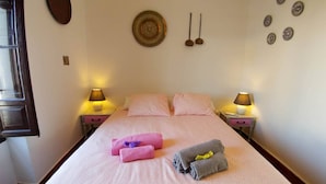 A neatly made bed with pink linens, two bedside lamps, and a wall clock. - Fantastic Penthouse in Plaza Elvira next to the Cathedral  (Sevilla)