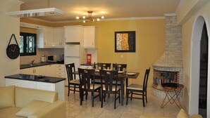Una cocina moderna con armarios blancos, un comedor con mesa y sillas, y una chimenea.