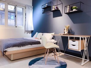 A modern bedroom with a bed, a desk, and shelves.