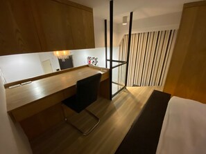 A modern hotel room with a wooden desk, a black chair, a large mirror, and a window with striped curtains. - Ha Ha Cat Home Shipai (Taipei)