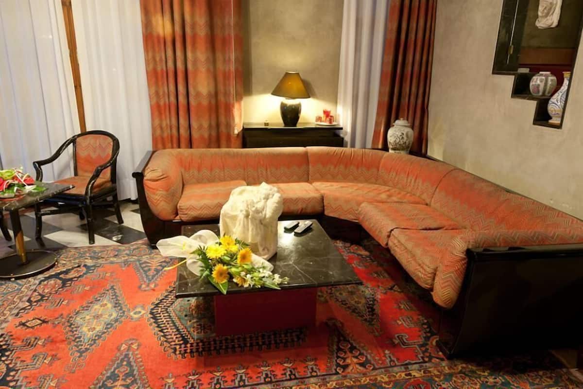 A living room with a curved sofa, a small table with a vase of flowers, and a lamp on a side table.