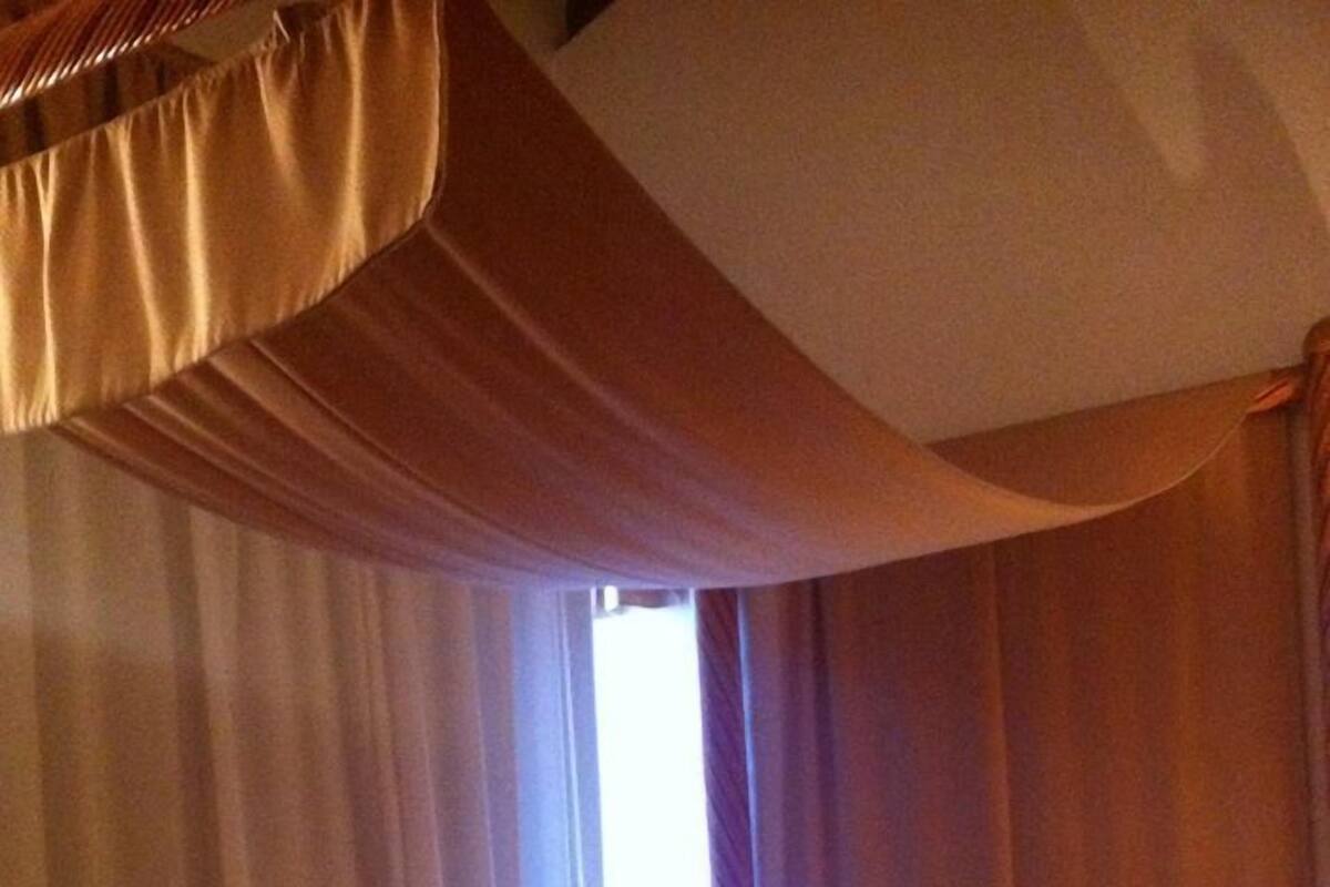 A hotel room with a bed, curtains, and a window.