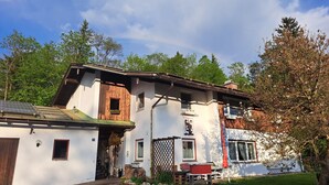 Un edificio de dos pisos con fachada de madera, una chimenea visible y un pequeño balcón.