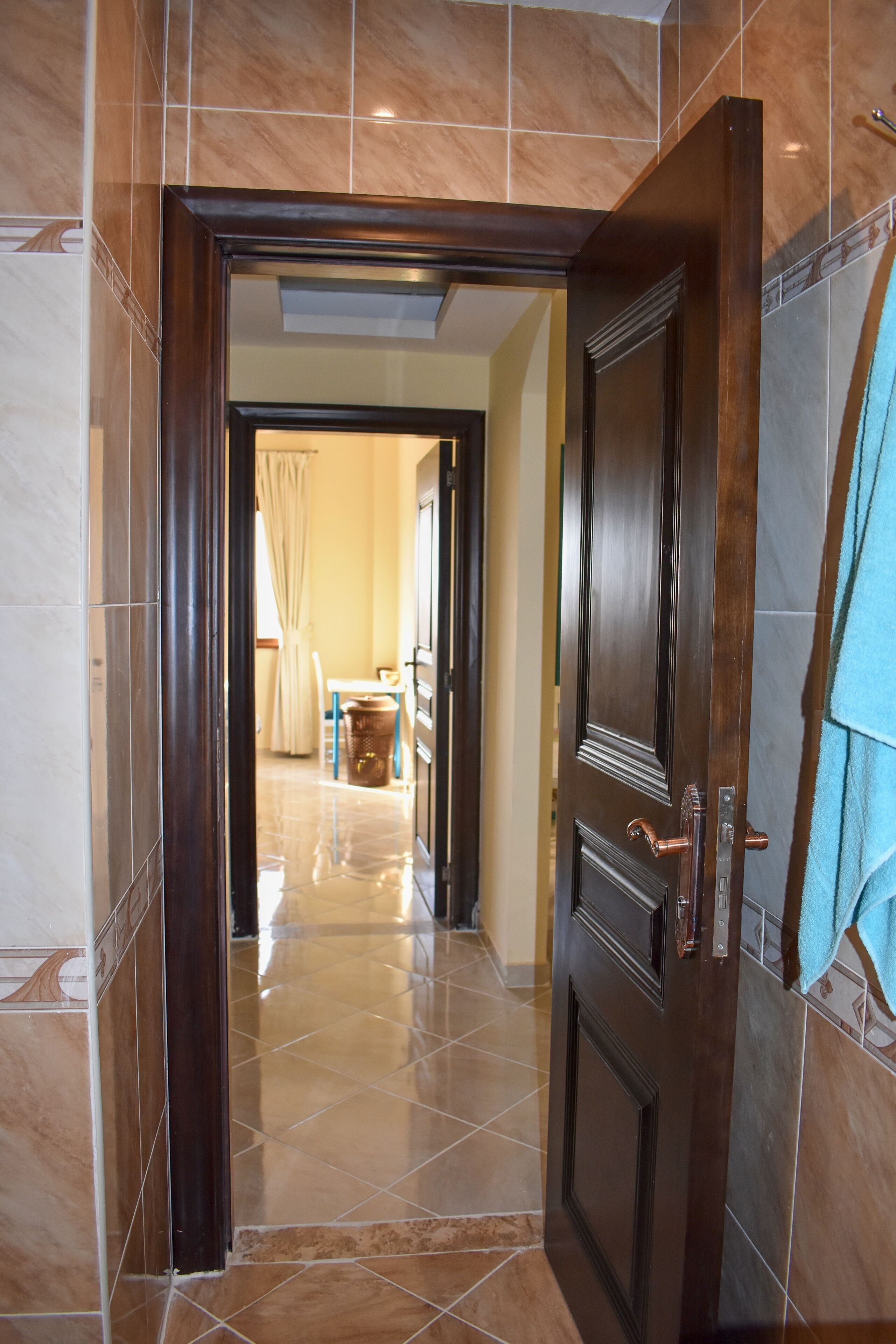 Un couloir avec une porte en bois qui donne sur une pièce contenant un lit et une fenêtre.