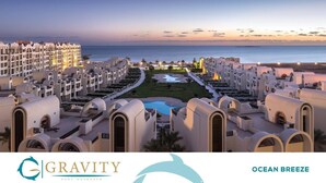 A resort with multiple white buildings, a central pool, and a view of the ocean. - One bedroom "Beach Haven" in 5-stars resort with pool and private beach (Sahl Hasheesh)