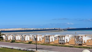 A beachside hotel with sun loungers and a pier in the background. - One bedroom "Beach Haven" in 5-stars resort with pool and private beach (Sahl Hasheesh)